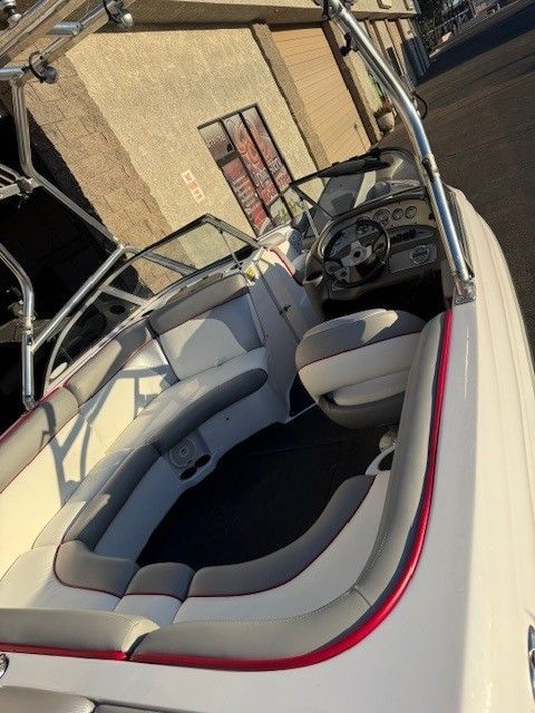 A white boat interior with gray and red accents. The boat has seating, a steering wheel, and a windshield.