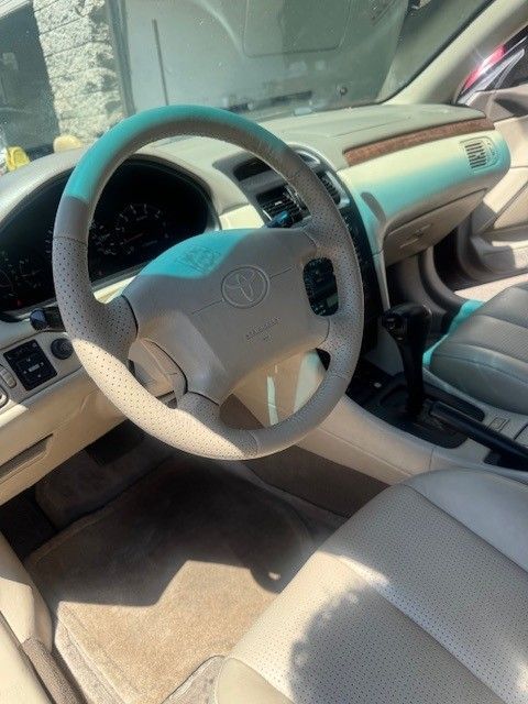 Tan interior of a Toyota Avalon, showing the steering wheel, dashboard, and seats. Beige and brown colors are prominent.