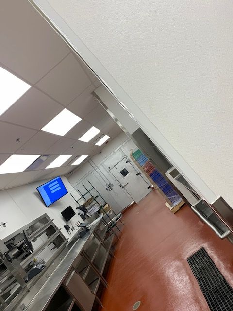 Commercial kitchen with stainless steel appliances, red floor, and overhead ventilation.