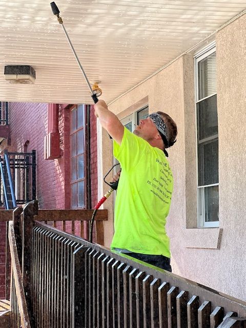 Man in neon shirt spraying a building ceiling.