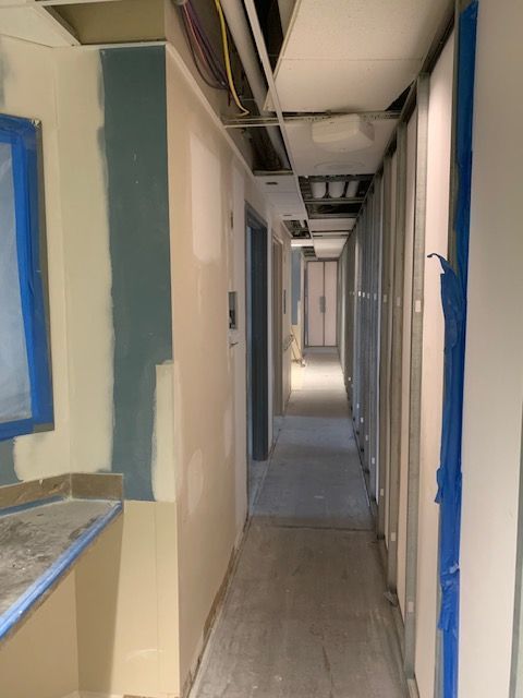 Interior hallway under construction; drywall, unfinished ceiling, blue tape.