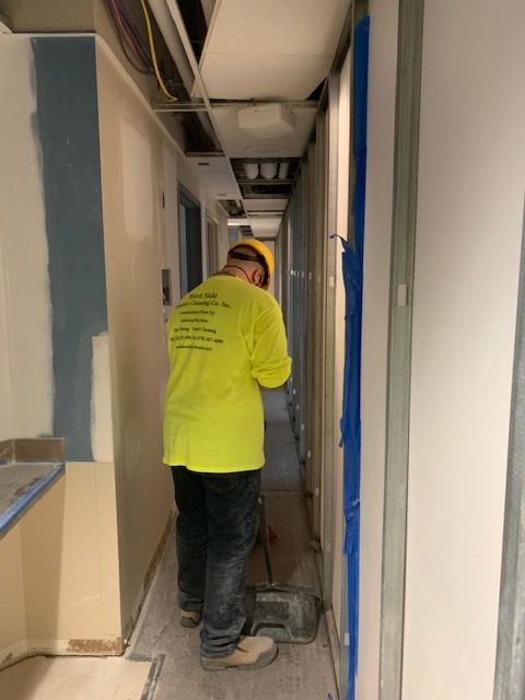 Worker in a yellow shirt and hard hat working on a construction project in a narrow hallway.