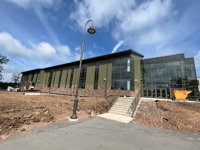 Modern building with stone accents and glass windows under a blue sky, construction ongoing.
