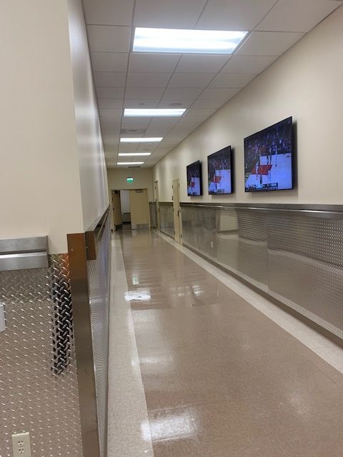 Hallway with monitors, light beige walls, shiny floor, and stainless steel accents.