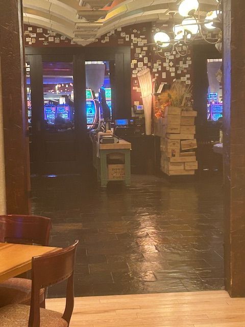 Interior view of a casino through an archway, with slot machines visible in the background.