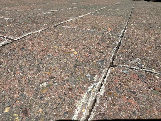 Close-up of rough, cracked concrete pavement with a gritty brown and gray surface