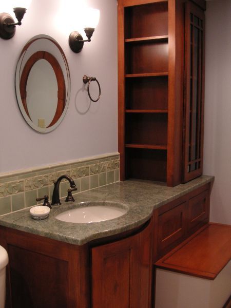 Bathroom vanity with round mirror, wall sconces, granite sink counter, and built-in wooden shelves