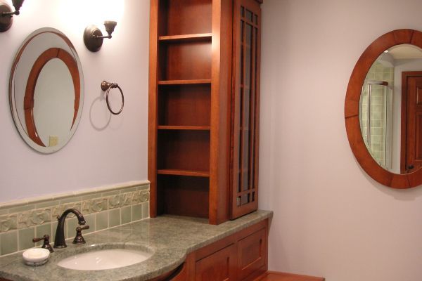 Bathroom vanity with oval mirrors, granite counter, sink, and wooden cabinet shelves