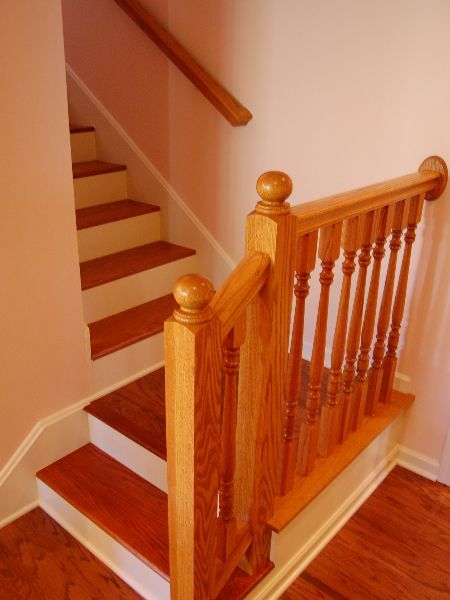 Wooden staircase with polished banister and white walls in a home interior