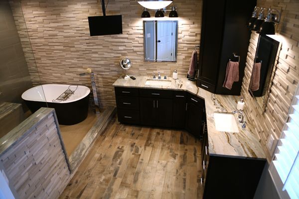Modern bathroom with stone walls, wood floor, black vanity, round tub, and large mirror