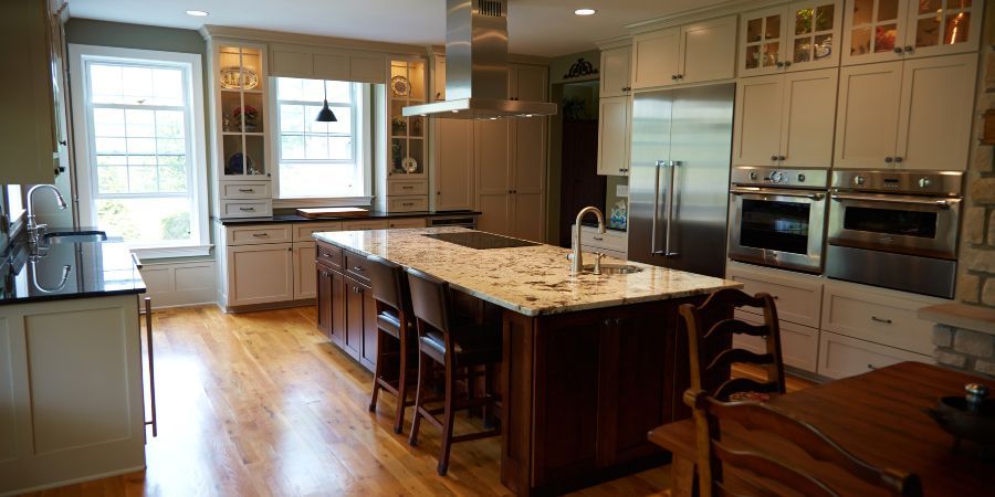 Spacious modern kitchen with a large island, wood floors, white cabinets, and stainless steel appliances