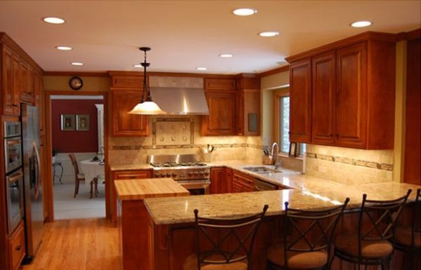 Warm kitchen with wooden cabinets, granite island, pendant light, and bar stools