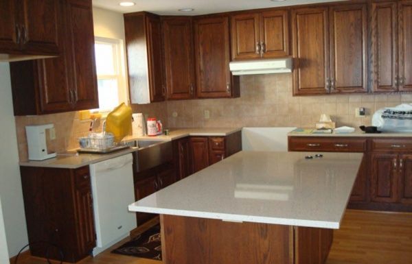 Modern kitchen with dark wood cabinets, white countertops, and a central island