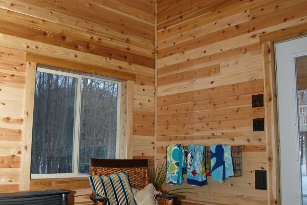 Wood-paneled room corner with a window, chair, and towels hanging on the wall