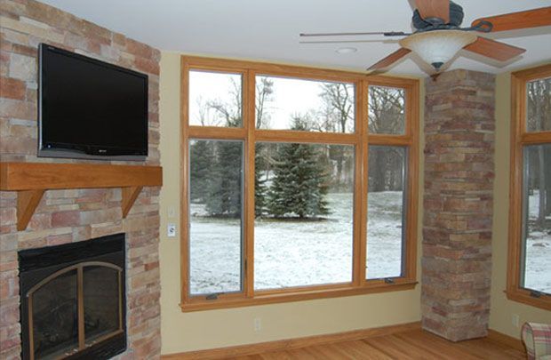 Living room with fireplace, wall-mounted TV, and large windows overlooking a snowy yard