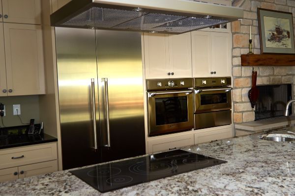 Modern kitchen with stainless steel appliances, granite island, and built-in ovens