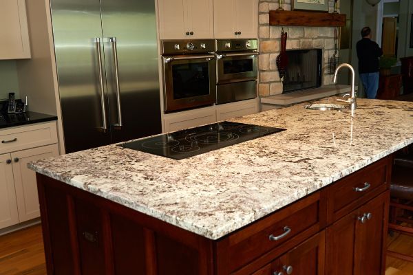 Modern kitchen with granite island, stainless steel appliances, and built-in cooktop