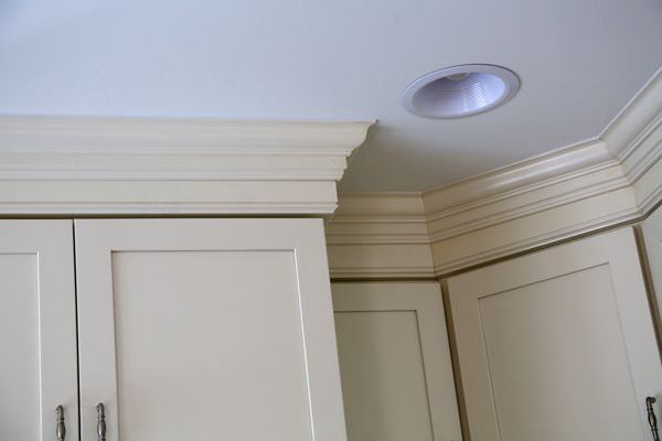 White kitchen cabinets with crown molding and a recessed ceiling light in the corner