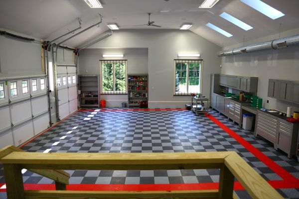 Empty indoor room with checkered floor, workbenches, and windows, viewed from behind a wooden railing