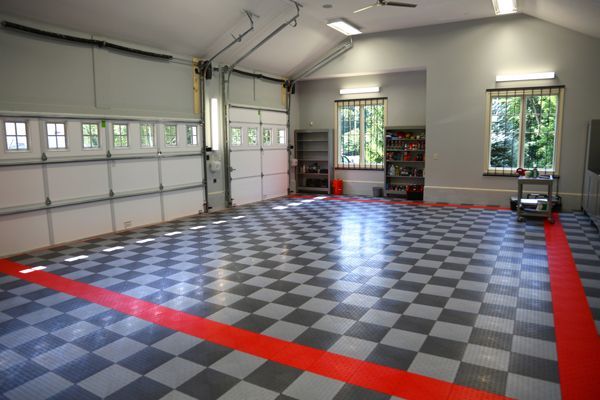 Empty garage with checkered floor and a red border, lit by windows and overhead lights