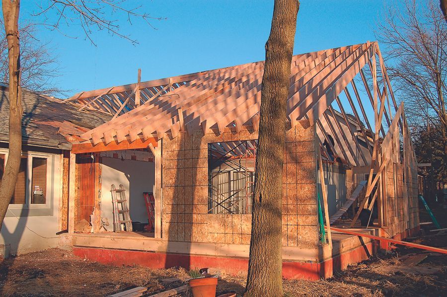 Partially built brick house with roof trusses in a sunny yard