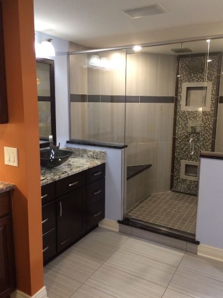 Modern bathroom with dark vanity, glass shower enclosure, and tiled floor
