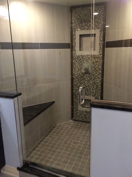Accessible shower with bench, grab bars, and tiled walls in a modern bathroom.