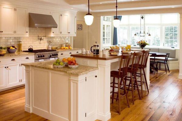 Bright, modern kitchen with white cabinets, island, and wooden floors, open to a dining area.