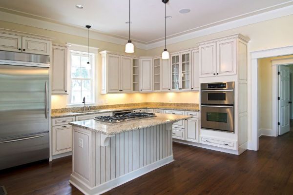 Bright white kitchen with large island, stainless steel appliances, and dark hardwood floors