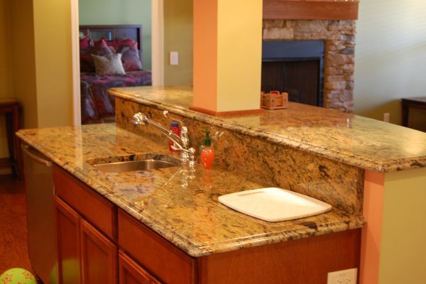 Granite kitchen island with sink and white bowl in a warm-toned open kitchen