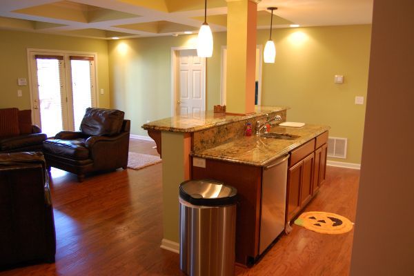 Open kitchen and living room with granite island, leather chair, and hardwood floors