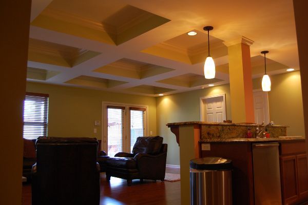 Warm living room with leather chairs, pendant lights, and a kitchen counter in the foreground.
