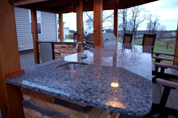 Granite outdoor dining table on a covered patio with chairs and backyard view