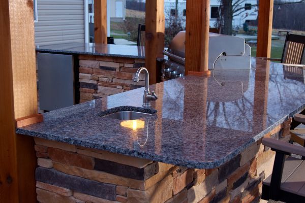 Outdoor granite countertop with built-in sink and stone base in a patio kitchen area