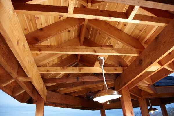 Wooden pavilion ceiling with exposed beams and a hanging light fixture