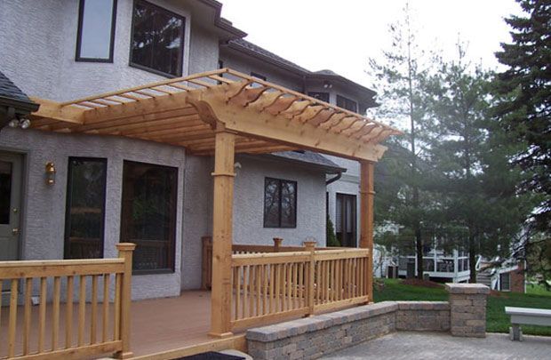Wooden pergola and deck attached to a stone house in a misty backyard