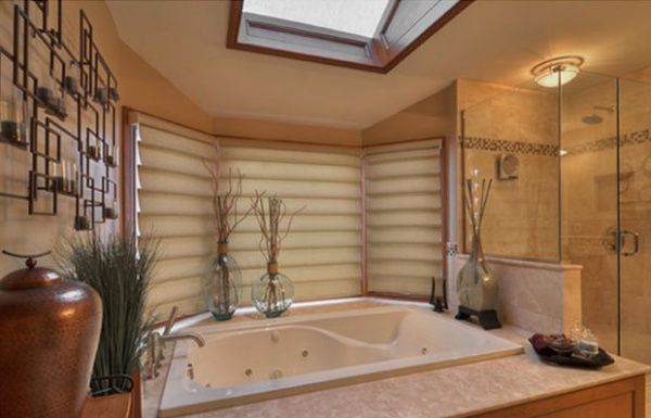 Spa-like bathroom with a soaking tub, skylight, beige tile, and decorative vases.