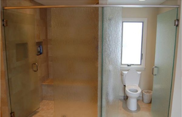 Accessible bathroom with a roll-in shower on the left and a toilet beside a window on the right.