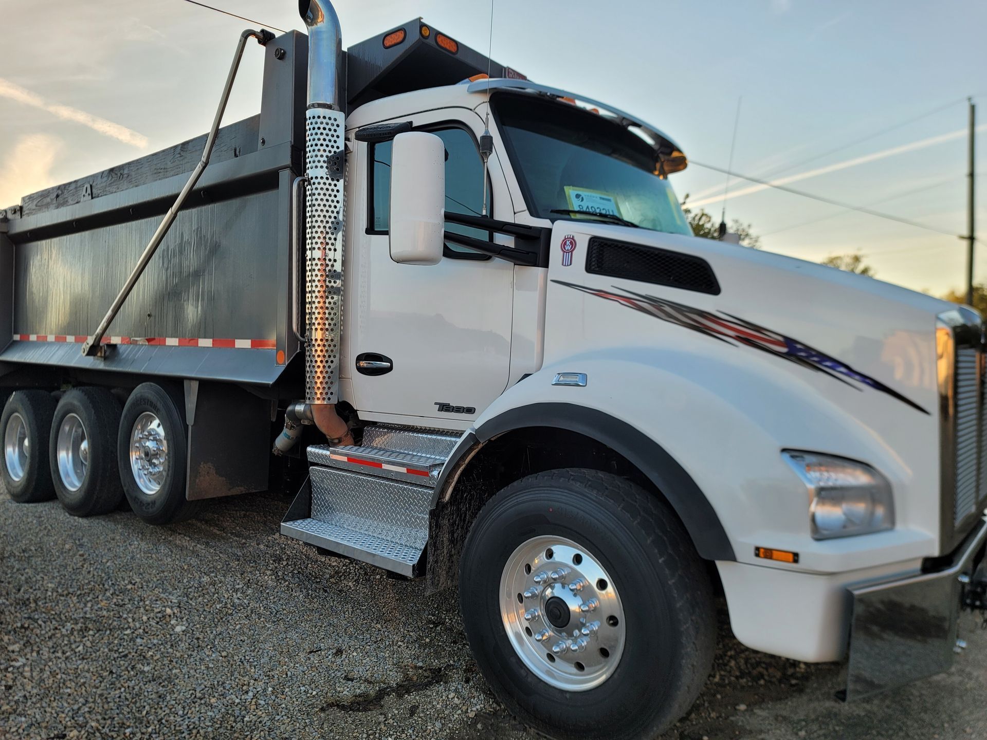 A white dump truck is parked in a gravel lot.