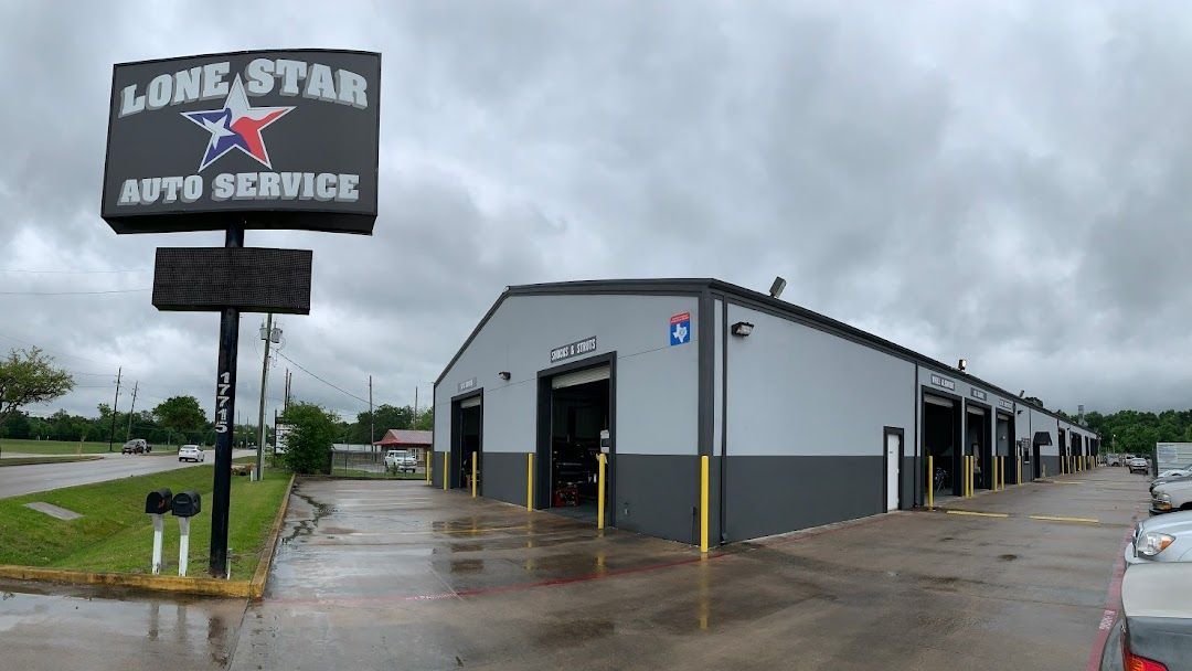 A gray and dark gray automotive repair shop under a cloudy sky, with a large