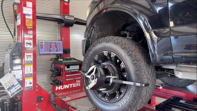 A truck wheel is mounted on a Hunter alignment machine in an auto repair shop.