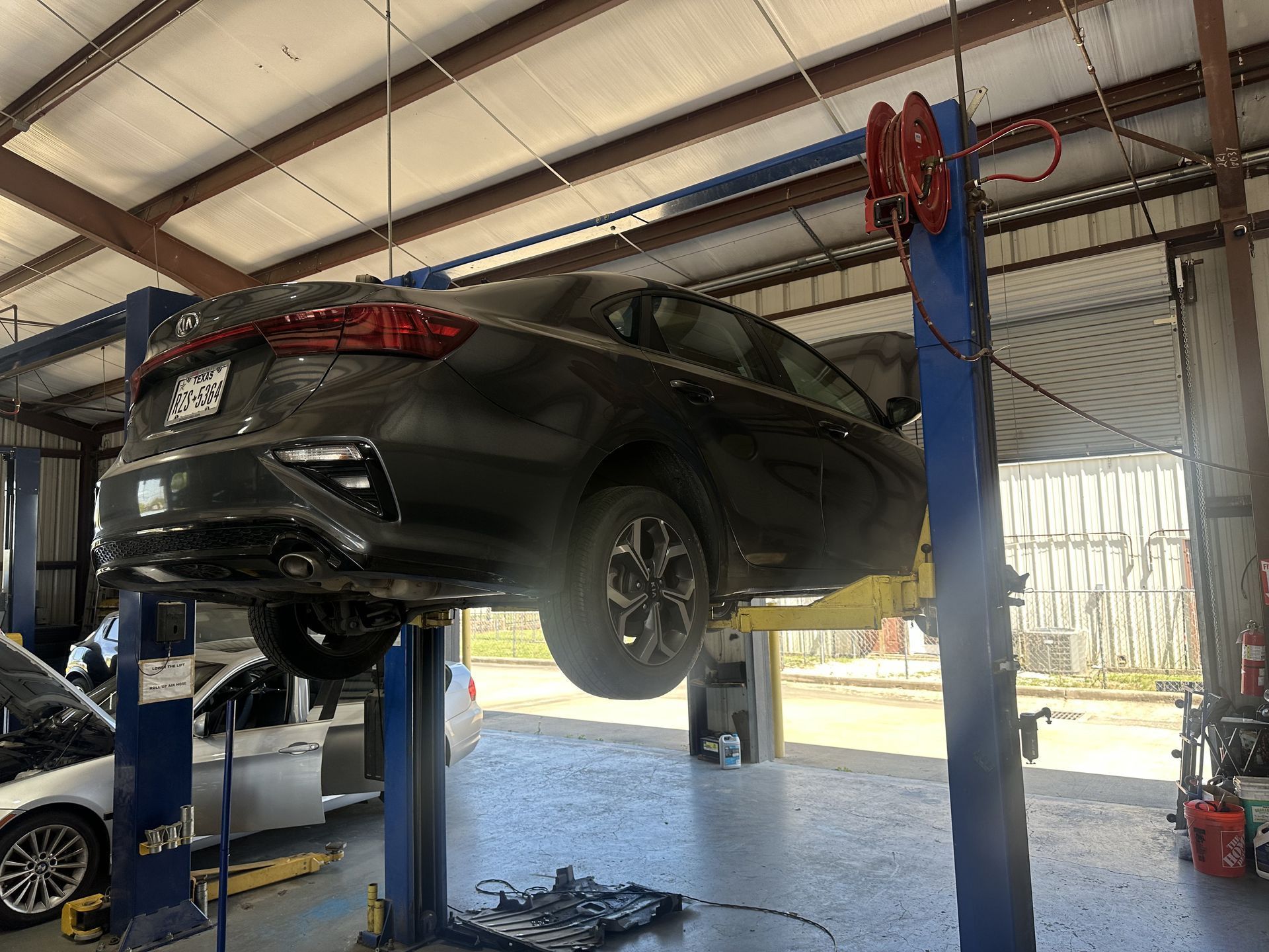Black SUV lifted on a blue hydraulic car lift inside an auto repair shop