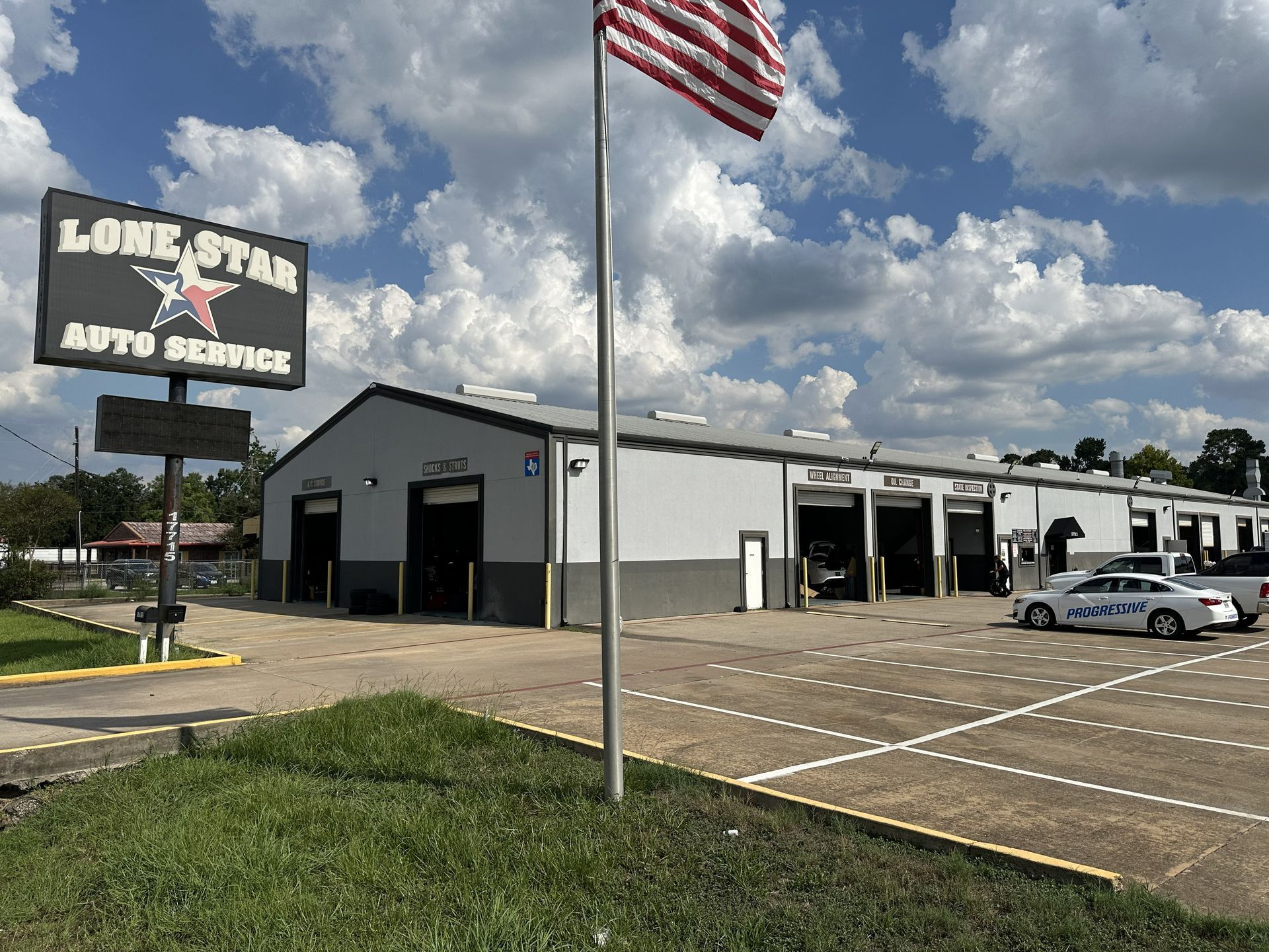 Lone Star Auto Service building under a blue sky with a flag pole and parking lot.