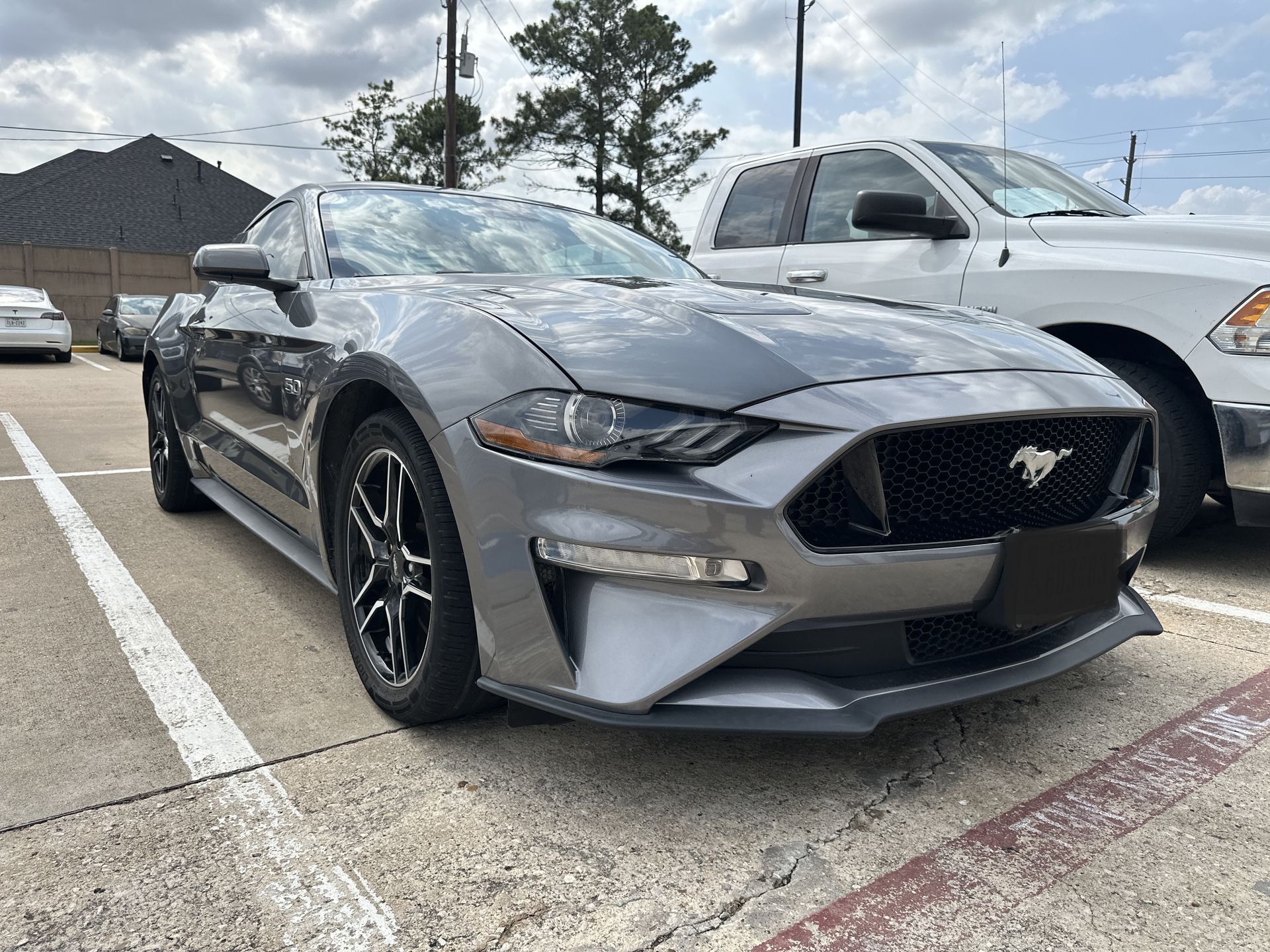 Gray Ford Mustang parked in a lot, front three-quarter view under a cloudy sky