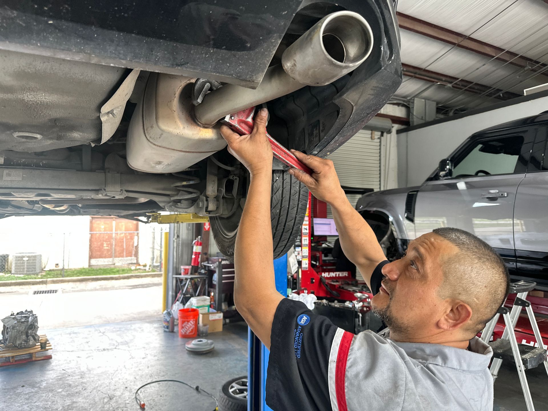 Mechanic working under a car, using a wrench in an auto repair shop