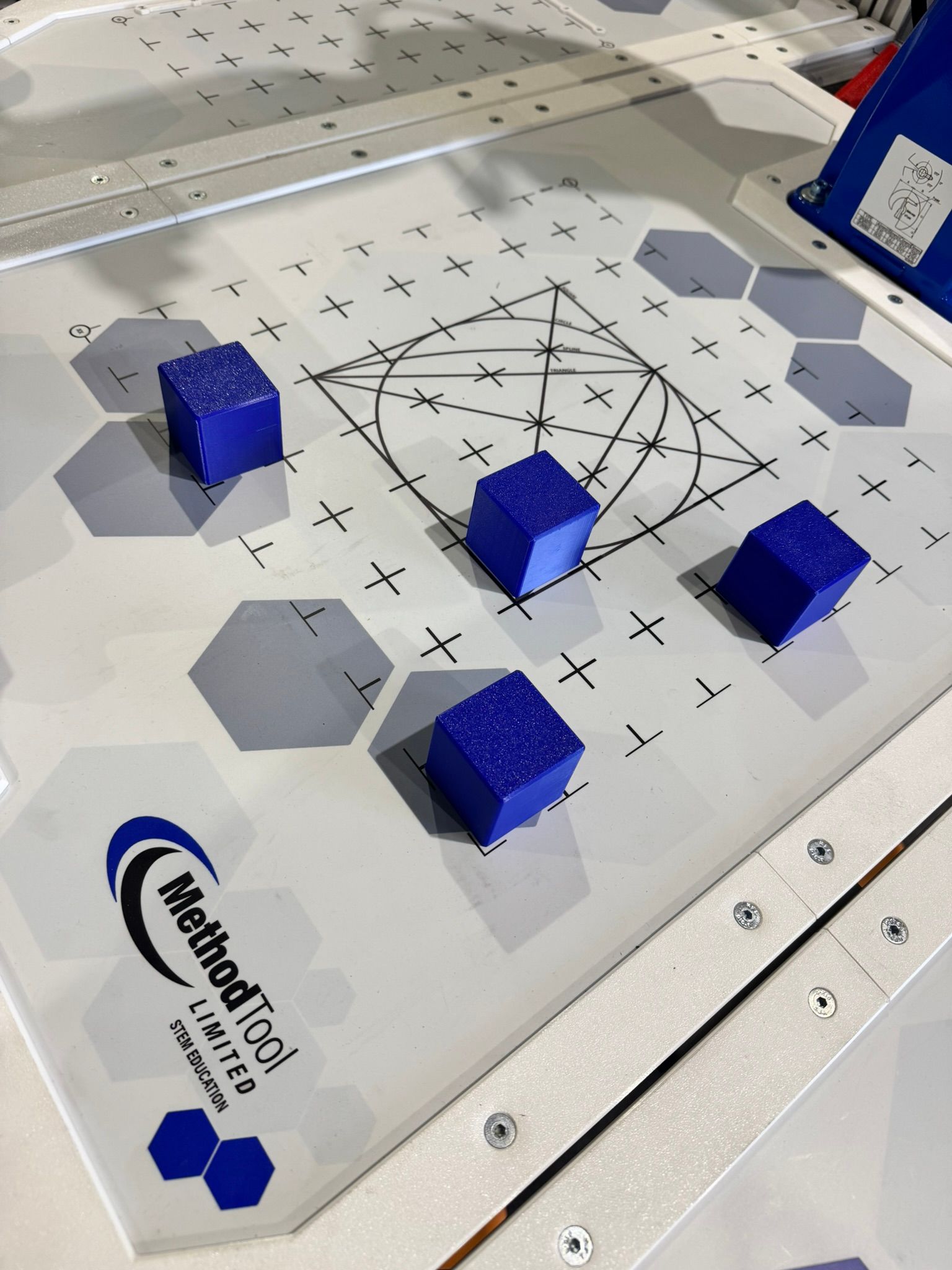 Blue cube markers on a printed calibration board with geometric lines and hexagonal targets.