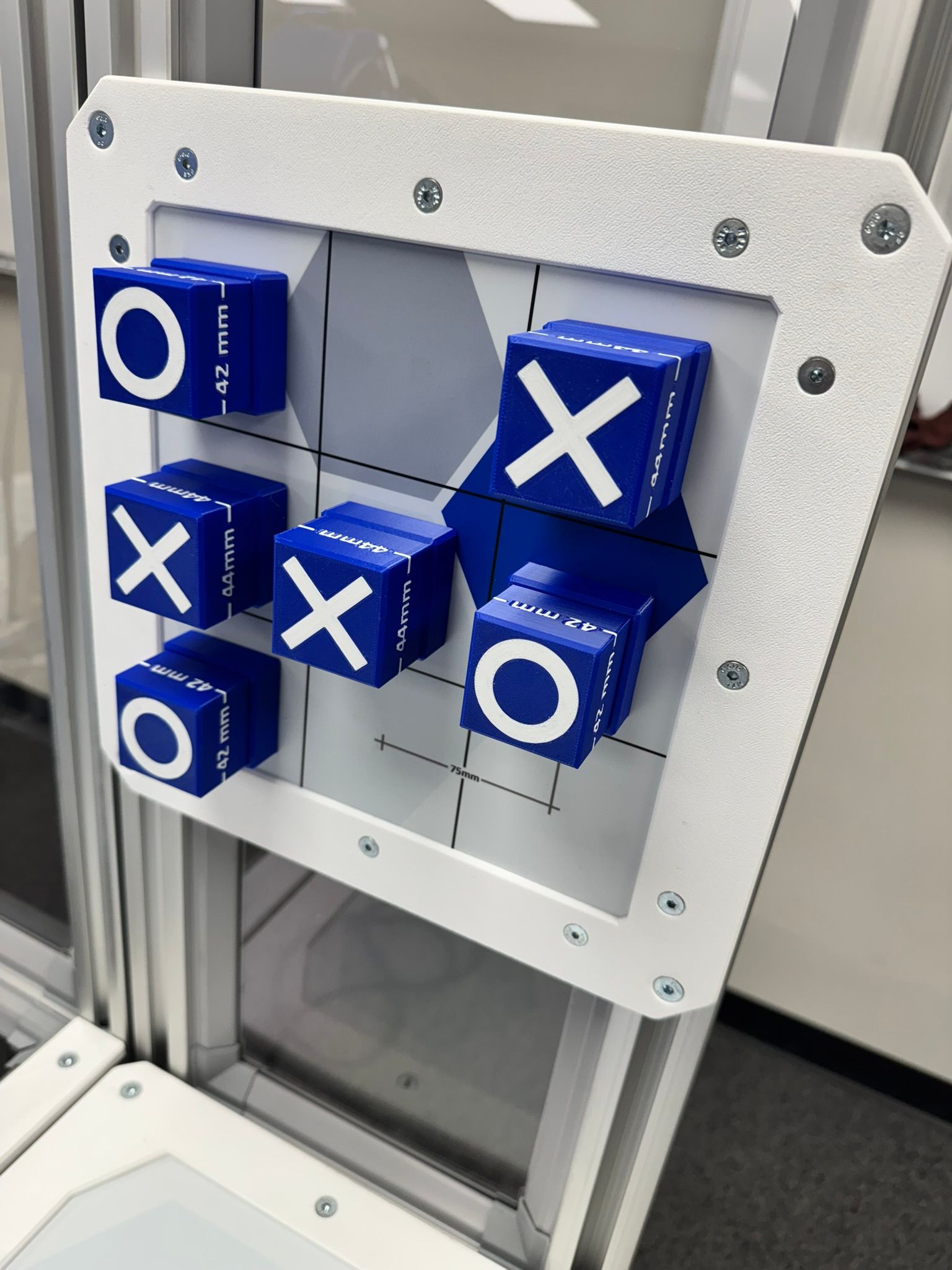 Blue tic-tac-toe blocks in a white framed puzzle on a metal stand.