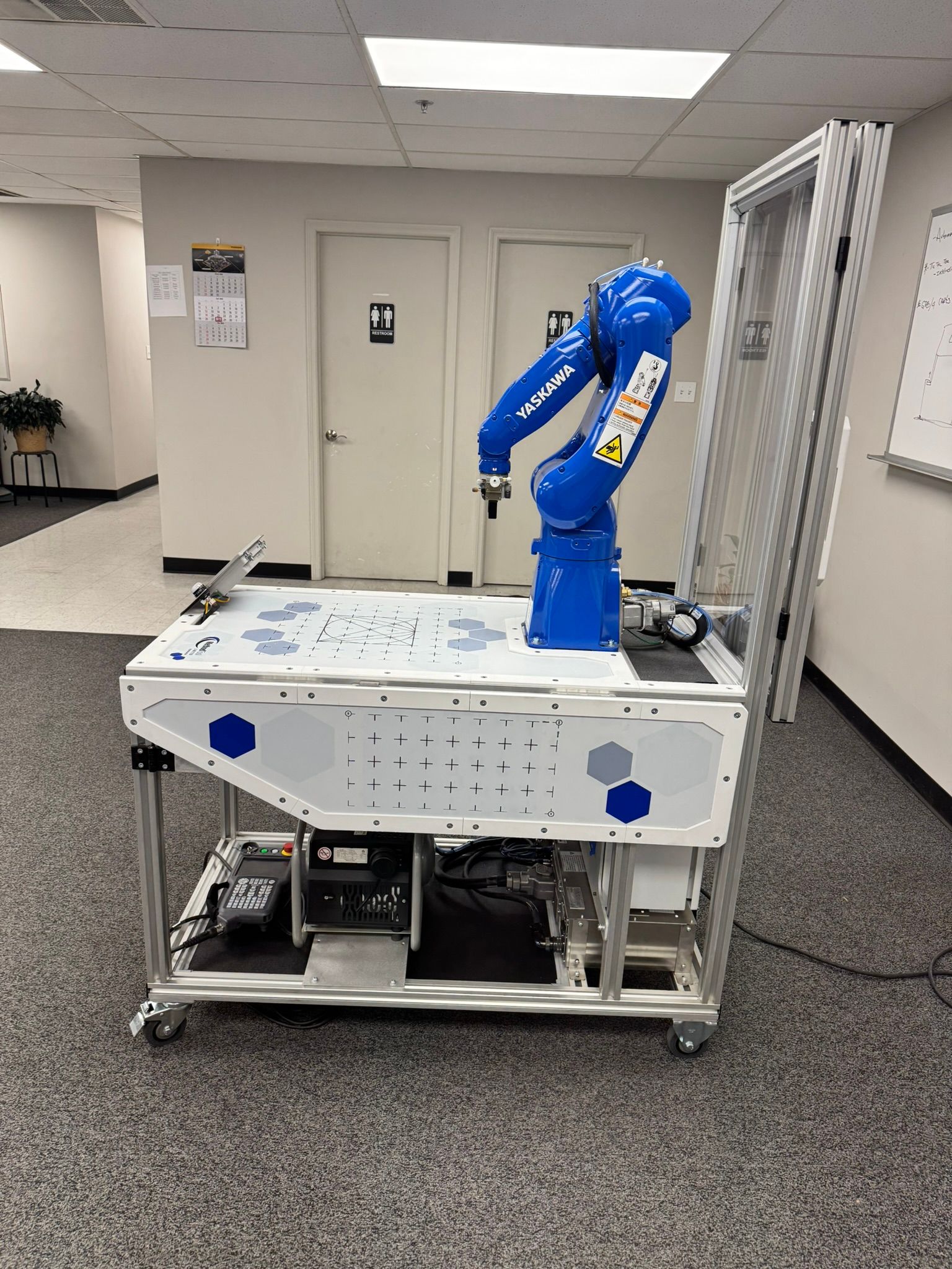 Blue robotic arm mounted on a wheeled cart in a lab or workshop room.