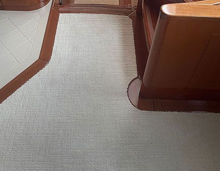 Light beige carpeted yacht floor with wooden trim and furniture.