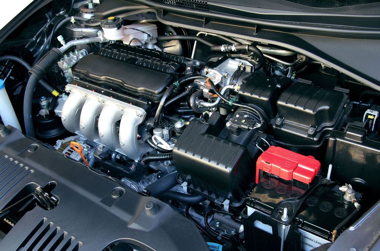 Car engine bay with a silver intake manifold and red battery terminal cover